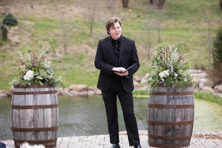 Reed standing between two whiskey barrels before the ceremony